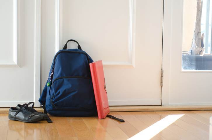 Back to school or ready for school concept with school bag and shoes by front door